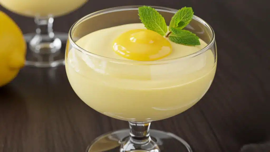 A dessert served in a glass, displaying vibrant layers of mousse and fruit, designed for a delightful dining experience.