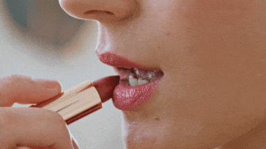 Applying nude lipstick on lips showing soft finish and precise application for a makeup routine
